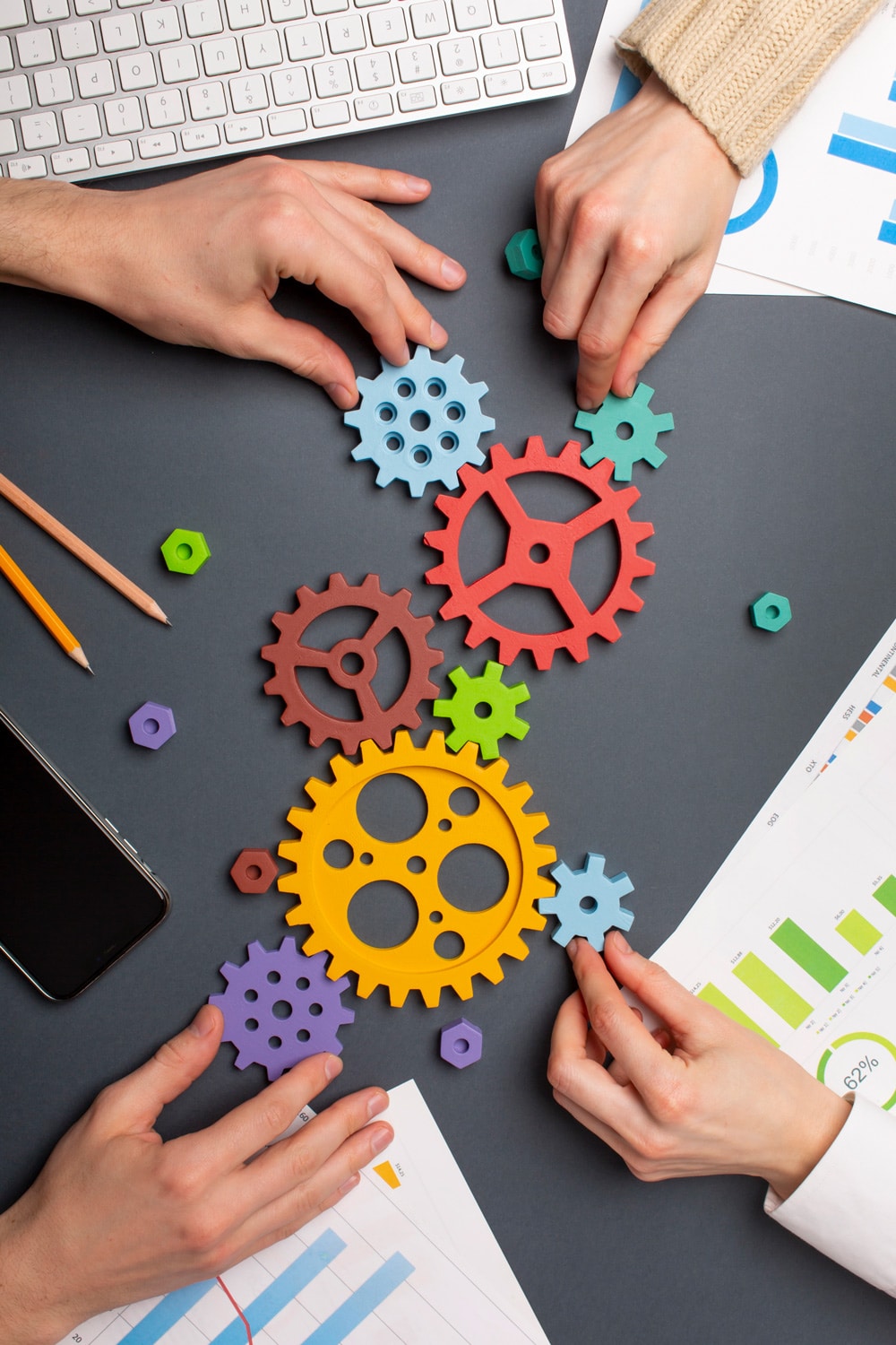 A group of hands holding cogwheels on a table